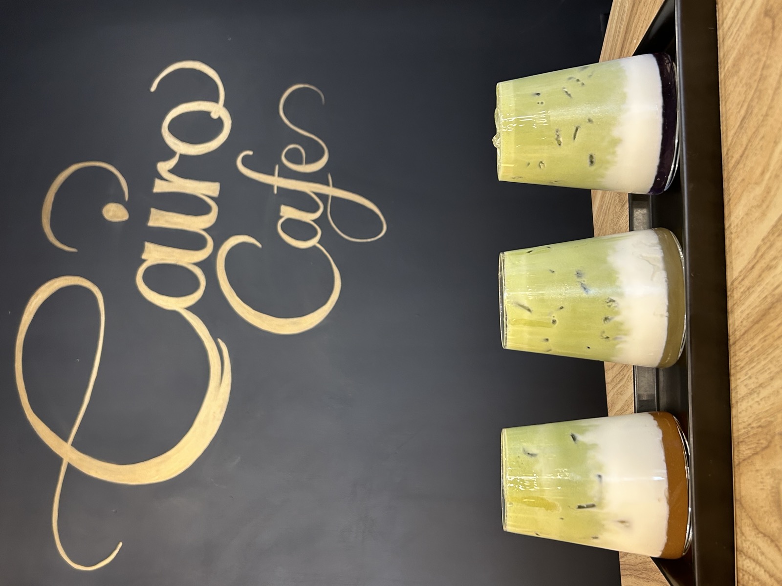 Three iced matcha lattes under the Cairo Café wall logo